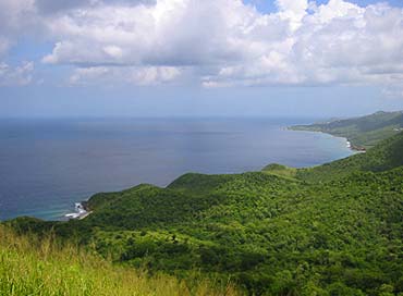 A view from a seaside cliff puts the viewer almost at cloud-height, with the sea horizon far in the distance and the green hills of St. Croix's north shore visible extending for miles.