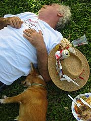 A camper and one of our camp dogs take a nap on the lawn, a plate of food nearby