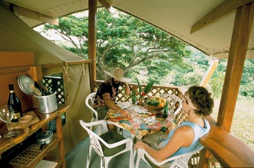A couple relaxes with a game of dominoes in their rainforest castle at Mt. Victory Camp.